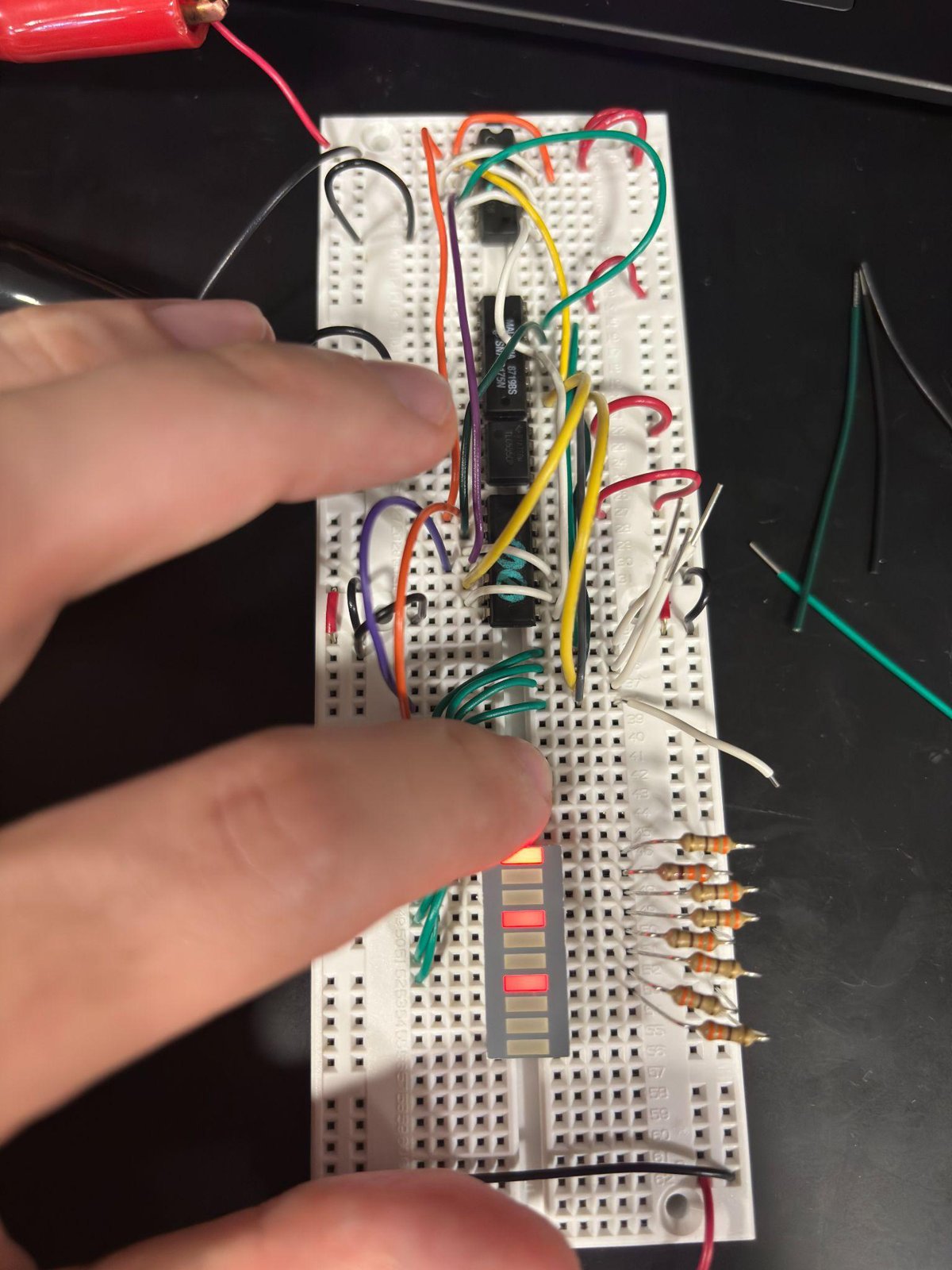 A finger pressing a key on the breadboard during testing.
